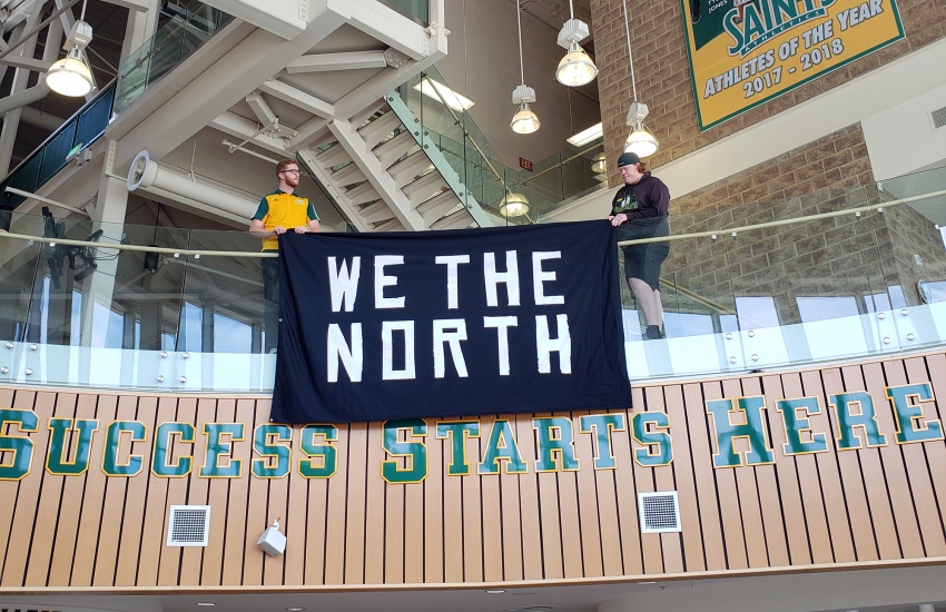 The 'We the North' flag being draped off the balcony at the SportsPlex entrance.
