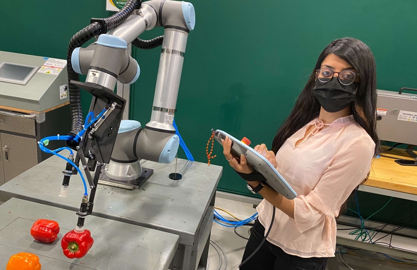 Khushboo Patel holds the controller she uses to direct the Universal Robotics UR10 collaborative robot.