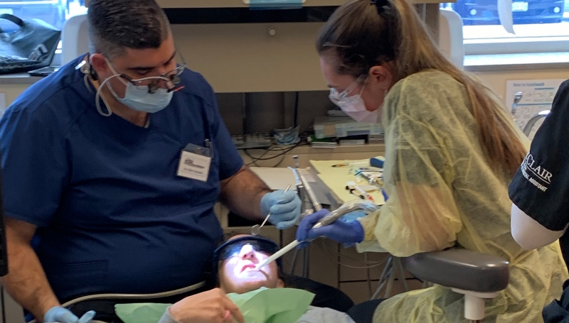 Dentist and hygienist cleaning the teeth of a patient.