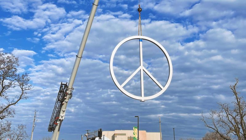 Crane lowering peace symbol into place