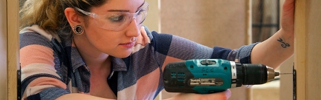 Girl drilling cabinet hinge in.